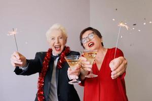 dos hermosas mujeres mayores maduras con estilo celebrando el año nuevo. diversión, fiesta, estilo, concepto de celebración foto