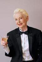 stylish mature sommelier senior woman in tuxedo with glass of sparkling wine. Fun, party, style, lifestyle, alcohol, celebration concept photo