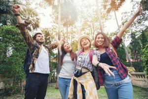 Asian Group of young people with friends backpacks walking together and happy friends are raised arms and enjoying a beautiful nature and cheering ,Relax time on holiday concept travel photo