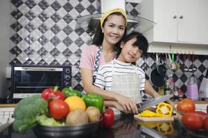 familia feliz tiene a papá, mamá y su pequeña hija cocinando juntos en la cocina foto