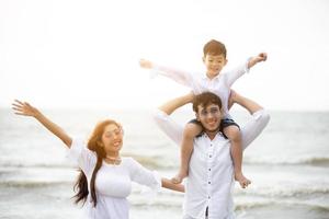 padres activos y personas actividad al aire libre en vacaciones de verano y vacaciones con niños.Familia feliz e hijo caminan con la diversión del mar al atardecer en la playa de arena. foto