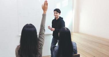 Los estudiantes del grupo levantan la mano para hacerle preguntas a un amigo para enseñar en la pizarra en el aula.