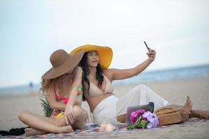 Women are taking photos and Selfie with friends on the sand beach in the summer.