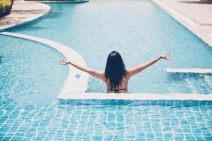 las mujeres usan bikinis y beben cócteles en el caluroso verano en la piscina. foto