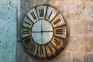 Reloj de sol antiguo con números romanos en una pared de piedra foto