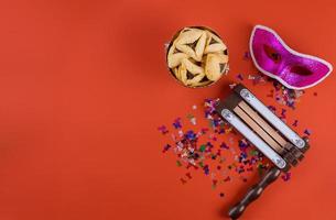 Traditional celebration on Jewish holiday Purim in the hamantaschen cookies, noisemaker and mask carnival photo