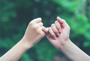 hands hook each other's little finger on nature background photo