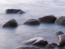 large smooth boulders on the shore in the fog long exposure