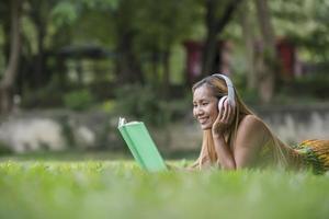Asian woman listening favorite music on headphones and reading a book. Happy time and relax. photo