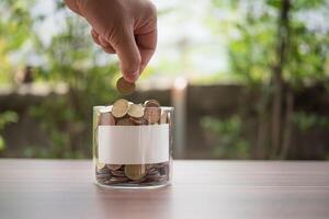 Hand  putting coins in jar with money stack step growing growth saving money photo