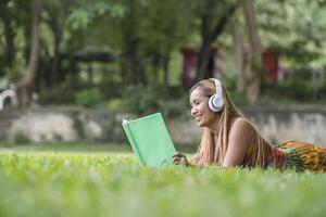mujer asiática escuchando música favorita en auriculares y leyendo un libro. tiempo feliz y relax. foto