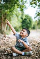 niño feliz sentado y pensando solo en el parque foto