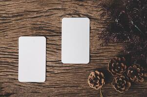 Se colocaron dos tarjetas en blanco con piñas secas sobre el fondo de madera. foto