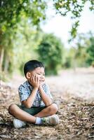 niño feliz sentado y pensando solo en el parque foto