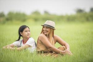 feliz madre con hija sentada en el parque de campo de hierba foto