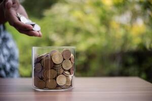 Hand  putting coins in jar with money stack step growing growth saving money photo