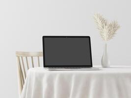 A laptop with a flower vase on the table photo