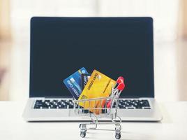 Shopping cart and credit card with laptop on the desk photo