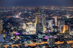 Paisaje urbano del edificio iluminado con grandes almacenes cerca del río Chao Phraya foto