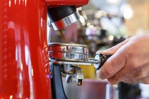 camarero en un café moliendo granos de café frescos en una máquina de molienda de café. foto