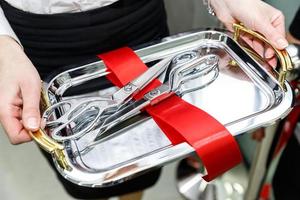 Female hands holding metal tray with scissors for official opening ceremonies with a cut of red tape photo