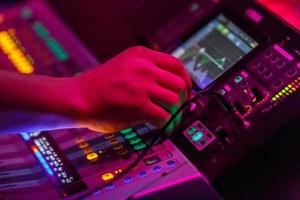 Sound engineer working with concert sound equiplment- audio mixing music console with backlit buttons. photo