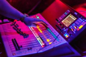 Sound engineer working with concert sound equiplment- audio mixing music console with backlit buttons. photo