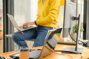 Programmers are using laptops to test the system in the office. She placed the laptop on her leg. photo