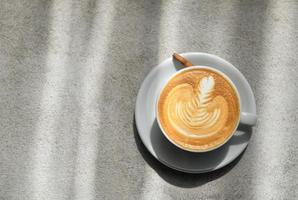 Latte coffee painted on top of the leaf placed on a concrete floor. photo