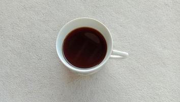 Foto de la taza de café negro en una taza blanca sobre un fondo blanco.