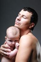 Happy young man holding a 4-5 months old baby in studio photo