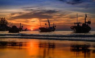 barcos de pesca de silueta en la puesta del sol. foto