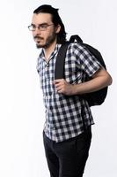 Young man with dark hair, beard and glasses wearing shirt and backpack photo