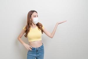 portrait beautiful woman wearing mask with hand presenting or pointing photo