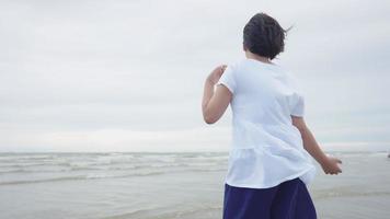 Linda chica asiática corriendo felizmente en la playa con alegría video