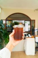 mano sosteniendo un vaso de café americano helado foto