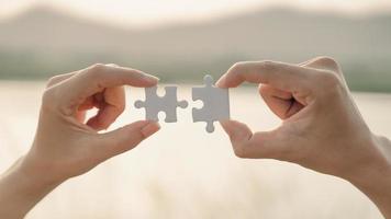 woman and man hand connecting a piece of jigsaw puzzle on mountain and lake background. symbol of association and connection concept. business strategy. photo