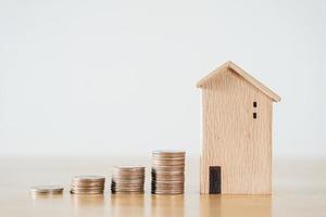 Wooden house and stacking coins on wooden table. saving money for buying house, financial plan home loan concept. photo