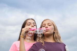 Two girlfriends blowing soap bubbles - carefree and fun time and friendship photo
