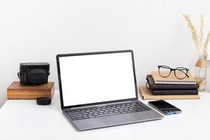 Blank laptop screen mock up, phone, camera and glasses. Work online, quarantine study, freelancer concept photo