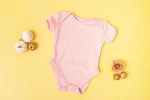 Baby clobodysuit mock-up with pumpkins on yellow background for your text or logo place in autumn season photo