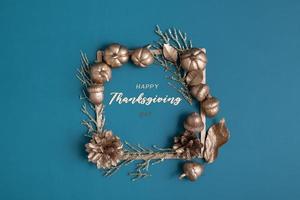 Happy Thanksgiving lettering with flat lay golden pumpkins and acorns on a turquoise background photo