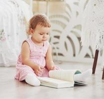 Beautiful little girl read book with her favorite bear on a soft plush blanket photo