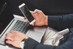 Man is a man working on a laptop and testing on mobile devices. photo