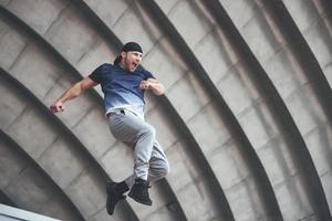 young man doing parkour jump in urban space in the city sunny spring summer day. photo