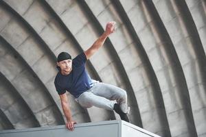 young man doing parkour jump in urban space in the city sunny spring summer day. photo