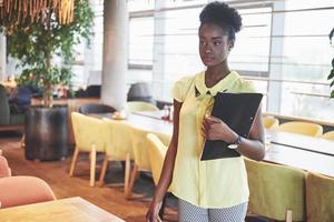 African American business woman stands with a folder in her hands photo