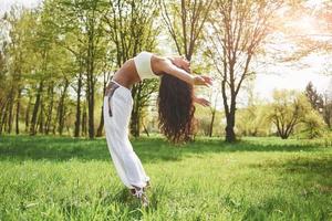 Practicing yoga of a beautiful girl in the morning on herbs under the sun's words. photo