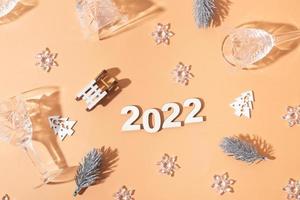 Festive new year flat lay with numbers 2022 and hard shadows with glasses and shiny decor photo