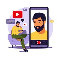 Man video blogger sitting on sofa with phone and recording video with smartphone. Different social media icons. Vector illustration in flat style.